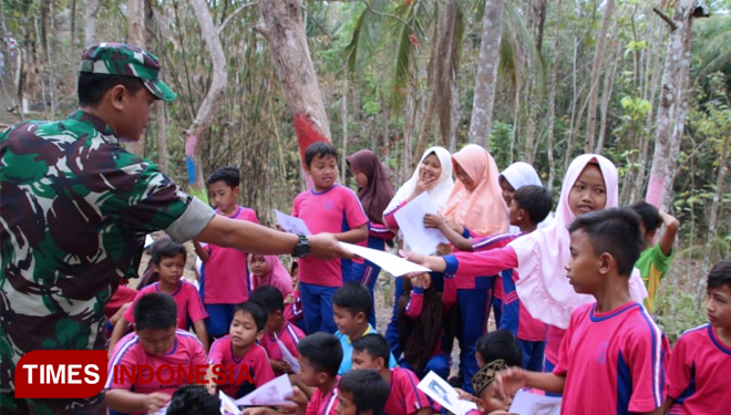 Sertu Mulyono sedang Bagikan Buku Kepada Siswa. (FOTO: AJP TIMES Indonesia)