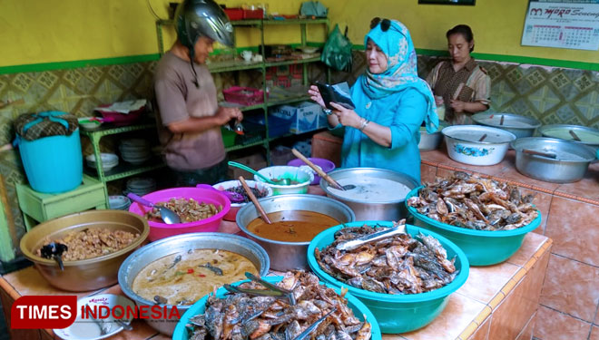 Seorang pembeli tengah memilih deretan lauk pauk iwak kali di warung Mak Ti, Kamis (3/10/2019). (Foto: Sholeh/TIMES Indonesia)