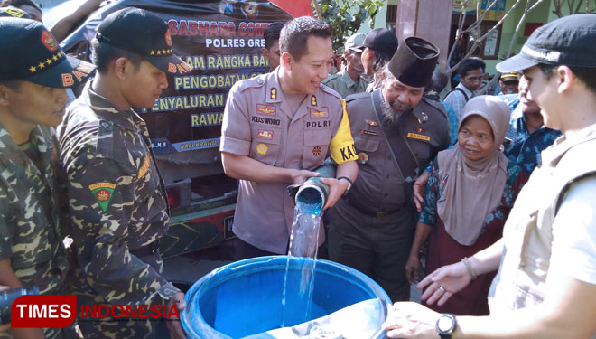 Kapolres Gresik AKBP Kusworo Wibowo saat membagikan air bersih ke warga Desa Tumapel, Kecamatan Duduksampeyan. (Foto: Akmal/TIMES Indonesia)