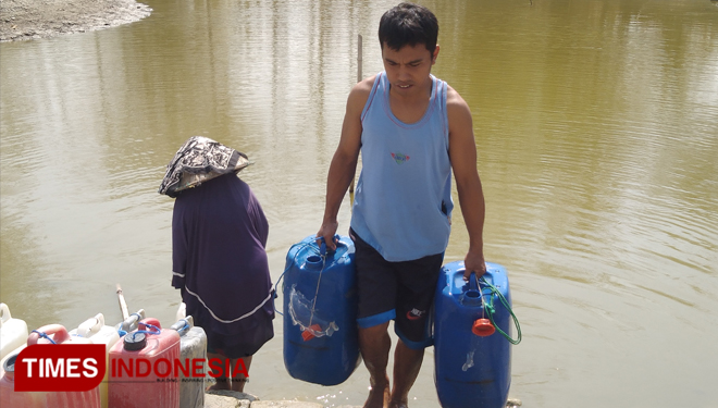 Warga Desa Tumapel saat mengambil air di telaga yang keruh. (Foto: Akmal/TIMES Indonesia).