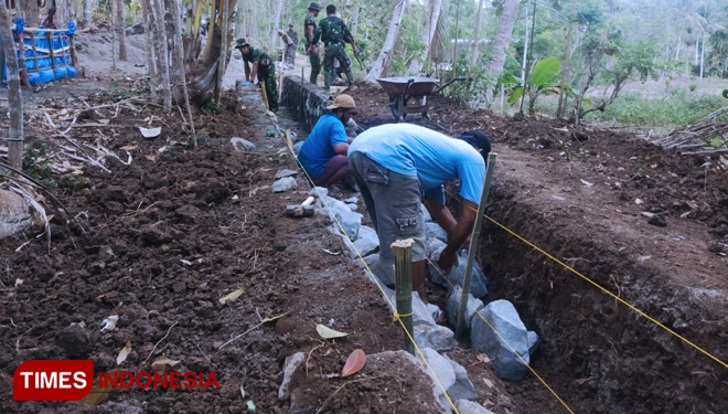 Menata Batu Dlm Pengerjaan Irigasi Di TMMD 106 Kodim 0818 Desa Donomulyo. (FOTO: AJP/TIMES Indonesia)