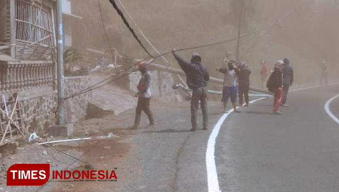 Petugas BPBD dan relawan mengimbau pengguna jalan agar tidak melalui jalan di Desa Sumberbrantas, Kecamatan Bumiaji karena terlalu beresiko untuk keselamatan diri. (foto: Muhammad Dhani Rahman/TIMES Indonesia) 