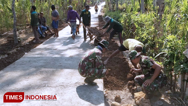 Penimbunan tanah di pinggiran jalan yang sudah di cor pada TMMD 106. (FOTO: AJP/TIMES Indonesia)