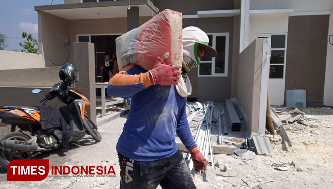 Pekerja proyek perumahan Trijaya Mas Property mengangkat satu zak semen merk Holcim. (FOTO: Safuwan/TIMES Indonesia)