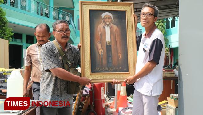 Pegawai Gedung Astranawa mengamankan potret Pendiri NU, KH Hasyim Asyari dalam proses eksekusi sengketa gedung, Rabu (13/11/2019).(Foto: Lely Yuana/TIMES Indonesia)