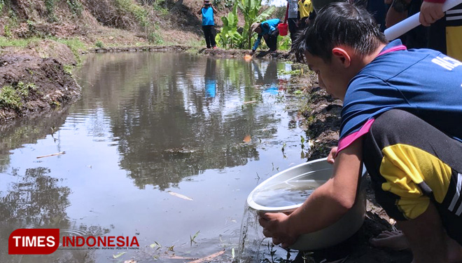 Para siswa saat menebar benih ikan lele dan nila di Sungai Brantas. (FOTO: Muhammad Dhani Rahman/TIMES Indonesia) 