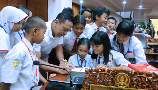 Siswa SDN Menanggal 601 Surabaya melihat secara langsung ruang sidang anggota dewan didampingi Wakil Ketua Komisi B DPRD Surabaya, Anas Karno, Senin (18/11/2019). (FOTO: Istimewa)
