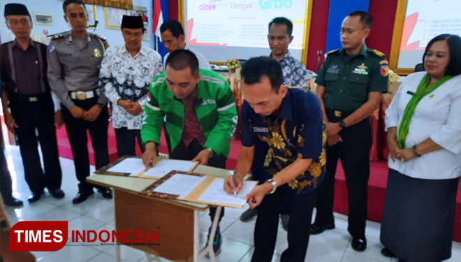 Syamhudi Arifin Kepala sekolah SMK Pgri 2 Ponorogo bersama Grab Benefits Jawa timur Dede Sadeli menanda tanggani kesepakatan Kerjasama ( MoU). (OTO: Evita Mukharomah/TIMES Indonesia)
