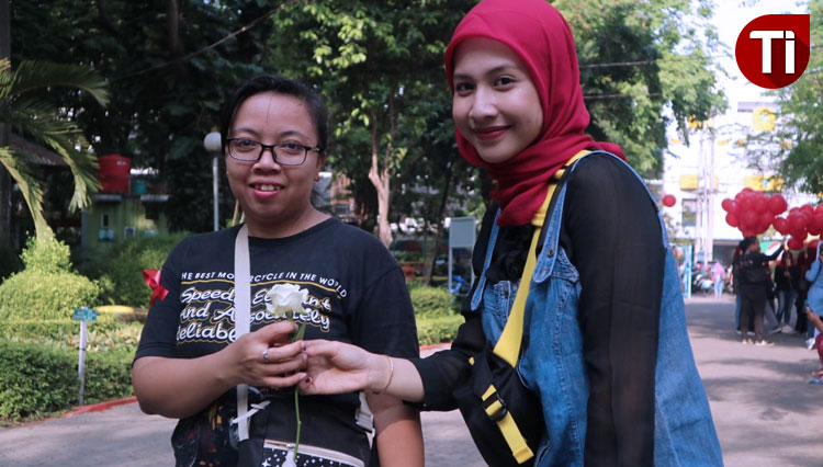 Mahasiswa KPI UIN Sunan Ampel Surabaya membagikan bunga di Taman Flora dalam rangka memperingati Hari AIDS Internasional, Minggu (1/12/2019). (Foto: Lely Yuana/TIMES Indonesia)