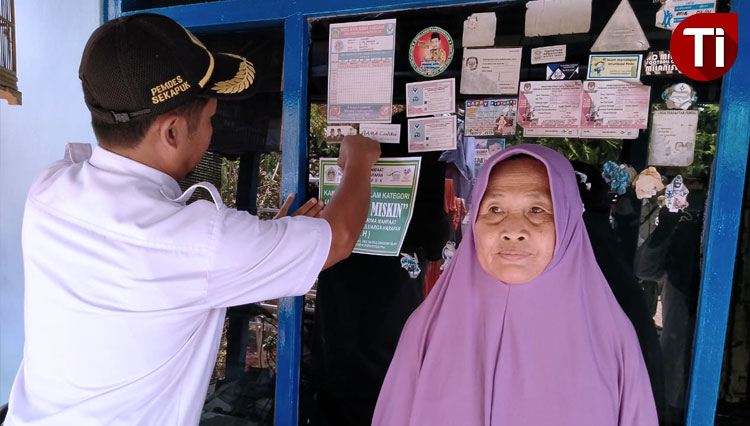 Pemdes Sekapuk saat menempel stiker di rumah keluarga miskin penerima bantuan. (Foto: Akmal/TIMES Indonesia).