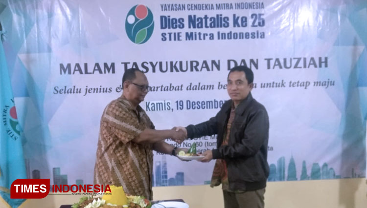 Ketua Yayasan Cendekia Mitra Indonesia Agus Paryanto (kiri) menyerahkan potongan tumpeng kepada Ketua STIE Mitra Indonesia Dr Koesharijadi (kanan). (FOTO: Reno Diqqi Alghazali/TIMES Indonesia)