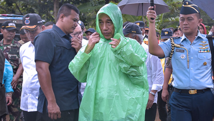 Dengan mengenakan jas hujan pemberian warga, Presiden RI Jokowi meninjau lokasi longsor di Desa Harkat Jaya, Kecamatan Sukajaya, Kabupaten Bogor, Jawa Barat, Selasa (7/1/2020) pagi. (FOTO: Humas Setkab).