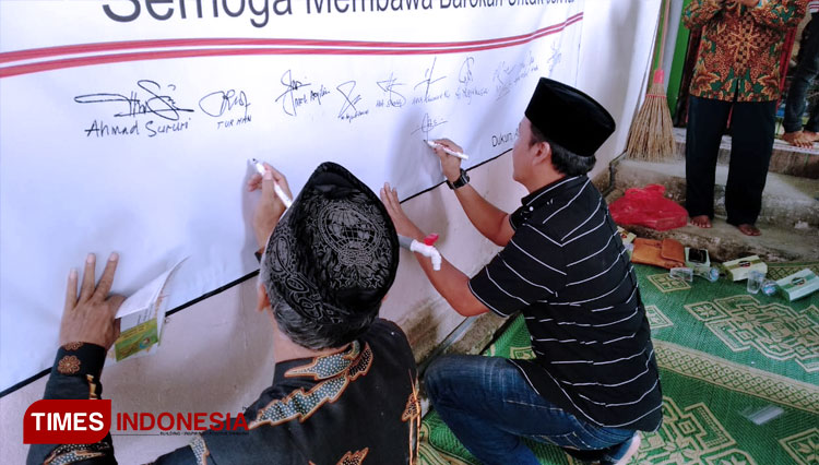 Pemilik saham saat membubuhkan tandatangan di kain putih sebagai wujud dukungan kepada pembukaan usaha percetakan yang oleh Mwc NU Dukun. (FOTO: Akmal/TIMES Indonesia).