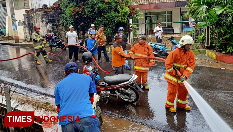 Petugas saat membersihkan lumpur yang membenam aspal jalan Songgoriti. (ist/TIMES Indonesia) 