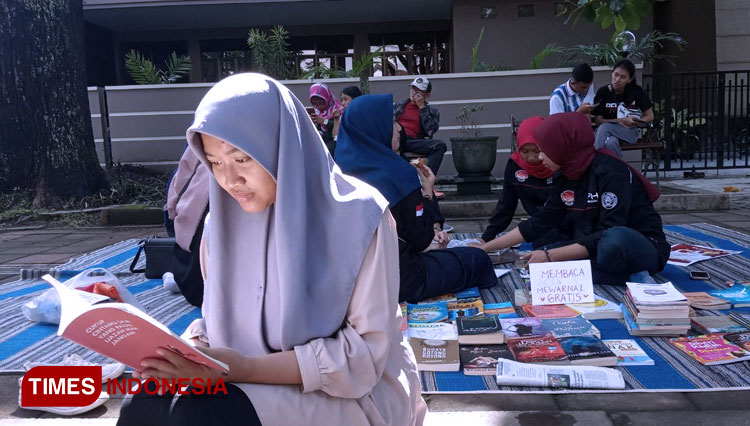 Pengunjung car free day membaca buku di lapak yang disediakan Imadiklus Universitas Malang, Minggu (2/2/2020). (foto: Delfi Nihayah/TIMES Indonesia)
