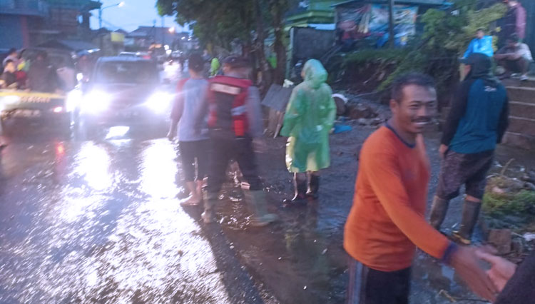 Petugas BPBD, Sabhara Polres Batu, TNI serta warga bahu membahu membersihkan material yang meluap ke jalan di Dusun Binangun, Desa Bumiaji. (FOTO: Istimewa/TIMES Indonesia)