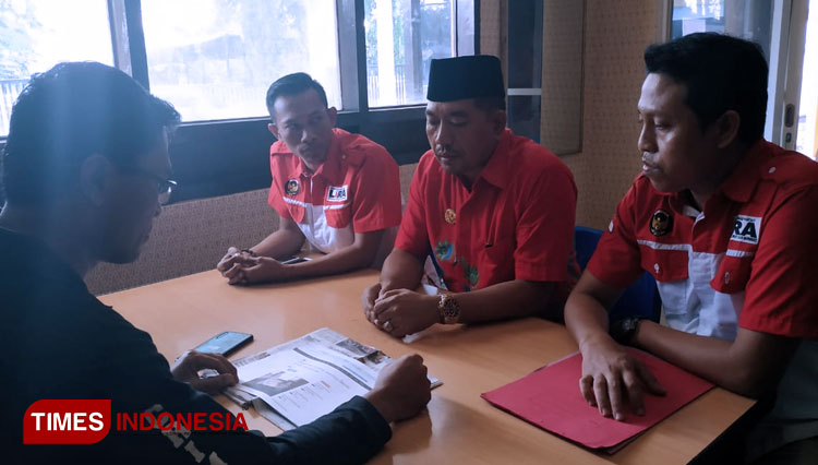 Kades Dringu, Bukhari Subhan (tengah), melaporkan dugaan pencemaran nama baiknya, di Mapolresta Probolinggo. (FOTO: Happy/TIMES Indonesia)