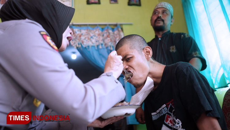 Polwan Polresta Probolinggo, menyuapi salah satu anak Janda Juama. (FOTO: C. Anwarsyah for TIMES Indonesia)