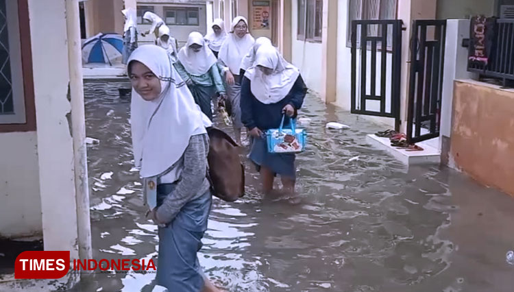 Sejumlah siswa meninggalkan sekolah akibat banjir yang merendam tempat mereka belajar. SMK Farmasi Indranayu menjadi salah satu yang mengalami banjir parah hingga aktifitas KBM terganggu. (Foto: Nurhidayat/TIMES Indonesia)