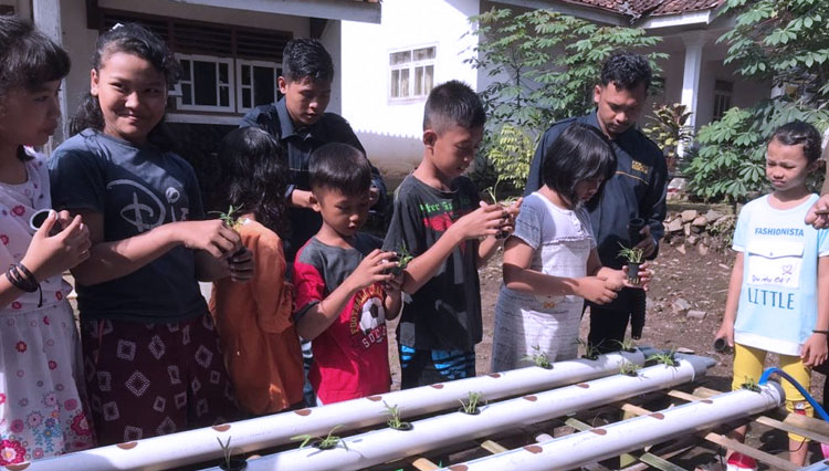 Mahasiswa KKN Kelompok 24 UM Jember bersama anak-anak menanam tanaman hidroponik di Rumah Kreasi Desa Sumber Kalong, Minggu (9/2/2020). (Foto: Humas UM Jember)