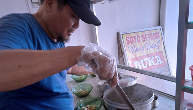 Odang sedang menyiapkan soto pelanggannya.
