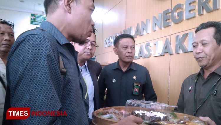 Kusnan Hadi saat memberikan seserahan jajan pasar kepada Pengadilan Negeri Surabaya sebagai simbol kemenangan gugatan BPJS pasa Selasa (10/3/2020). (FOTO: Khusnul Hasana/TIMES Indonesia)