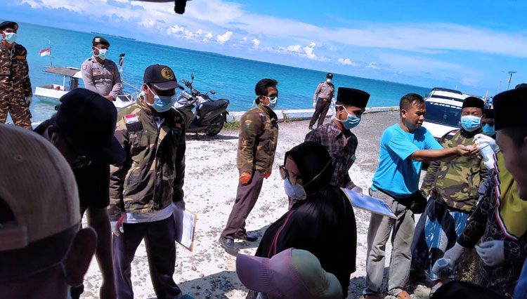 Pengurus GP Anor Raas bersama tim medis dan Forkompicam Raas saat bagi-bagi Hand Sanitizer kepada masyarakat di Pelabuhan Raas. (foto: TIMES indonesia)
