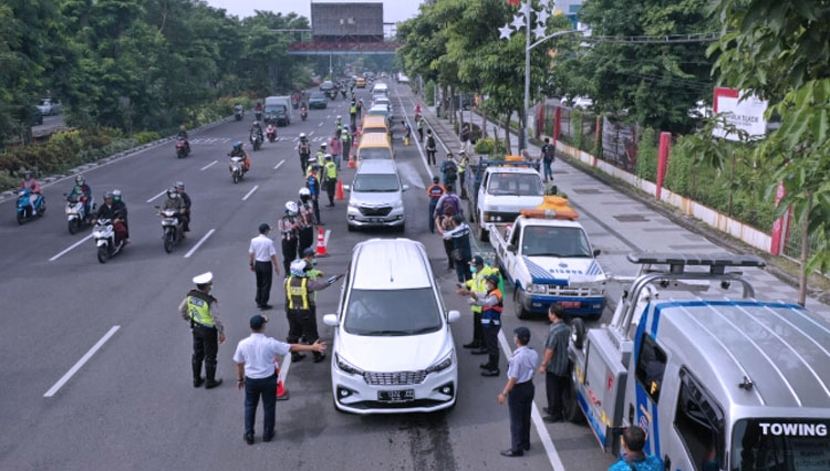 Suasana penyemprotan disinfektan untuk kendaraan bermotor di salah satu jalan protokol di Surabaya. (Foto: Istimewa)
