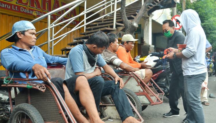 Pengacara Surabaya Sunarno Edy Wibowo membagikan paket sembako kepada para tukang becak di Area Pasar Kapasan, Surabaya, Kamis (16/4/2020). Candra Wijaya