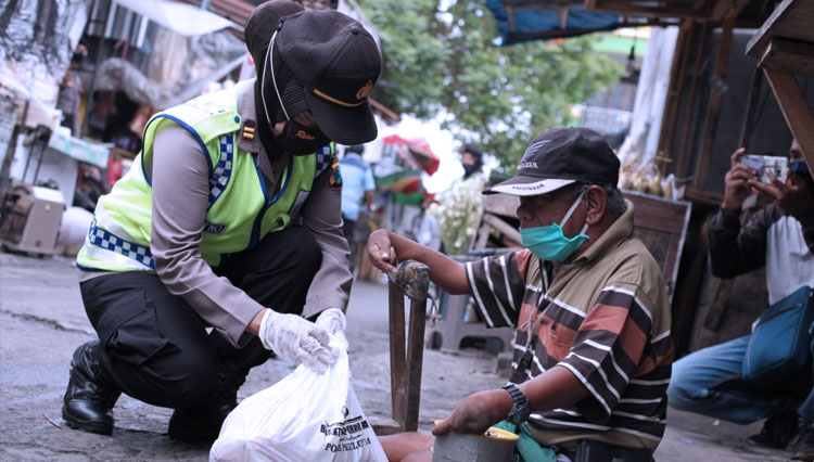 Tim Srikandi Polres Blitar Kota menyalurkan bantuan kepada difabel yang mereka temui di pasar, Minggu (31/5/2020). (Foto: Humas Polres Blitar Kota)