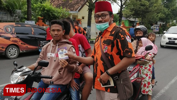 MPC Pemuda Pancasila Lamongan membagikan buku saku kepada pengguna jalan, dalam memperingati Hari Lahir Pancasila, Senin (1/6/2020). (FOTO: MPC Pemuda Pancasila Lamongan for TIMES Indonesia)