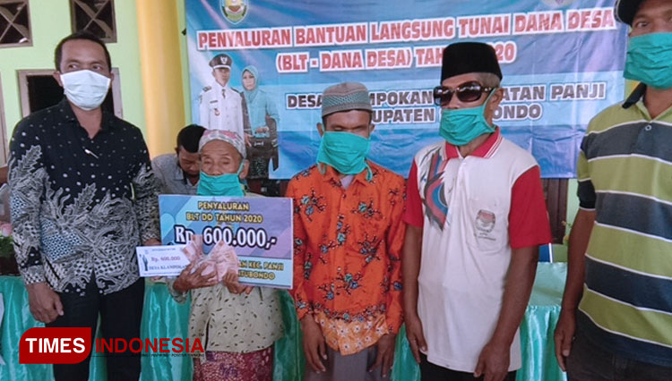 Adi Arso Kepala Desa Klampokan Kecamatan Panji, saat menyerahkan BLT Dana Desa. (Foto: Fawaid Aziz/TIMES Indonesia)