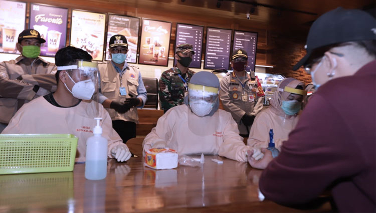 Petugas saat melakukan rapid test kepada anak muda yang nongkrong di kafe. (Foto: Humas Pemkot Malang)