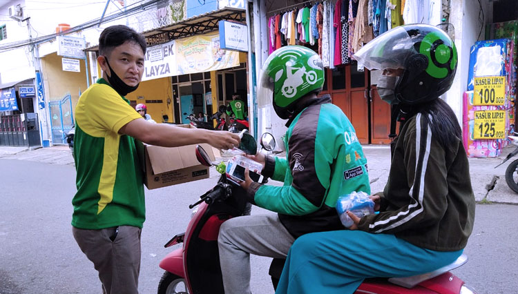 Daniel selaku Humas PDOI Jawa Timur saat membagikan nasi bungkus, masker dan hand sanitizer pada ojol (Foto : dok PDOI)