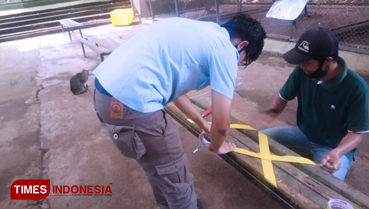Several staff putting some yellow cross band on the bench. (PHOTO: Erwin/TIMES Indonesia)