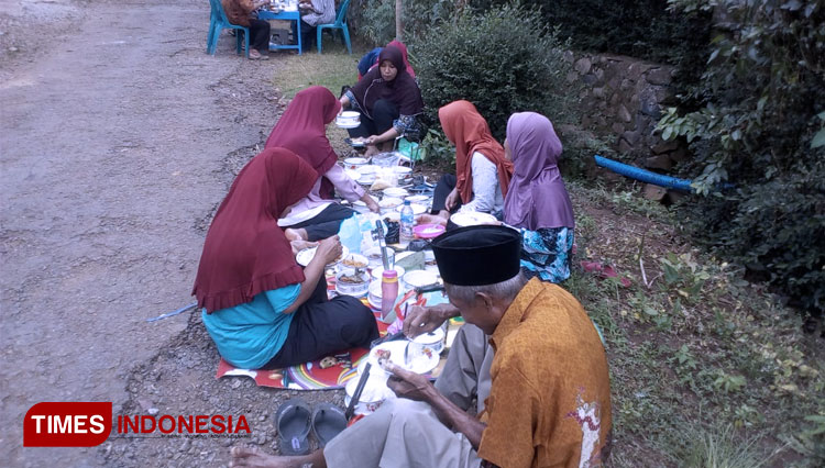 Kenikmatan warga Karanggedang dalam menyantap hidangan diacara memetri bumi apitan desa. (Foto: Hermawan Septianto/TIMES Indonesia)