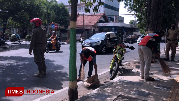 Sejumlah pemuda saat sedang menyapu di pinggir jalan di kota Tuban karena tidak memakai masker, Senin (06/07/2020)(Foto: Achmad Choirudin/TIMES Indonesia)