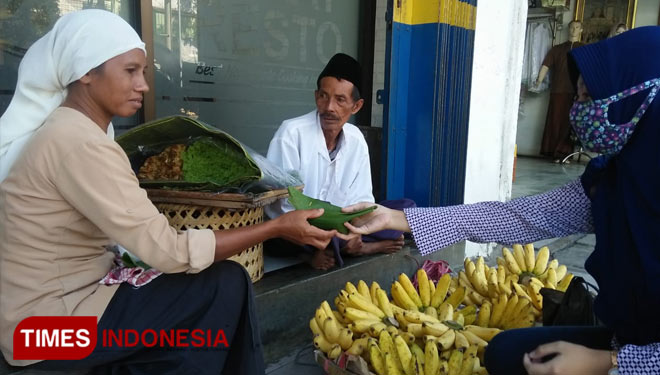 Ibu Tini Penjual jajanan tradisional Buggul saat melayani pembeli. (FOTO: Moh Bahri/TIMES Indonesia)