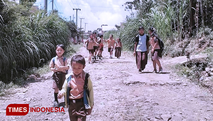 Pelajar SD di Desa Cepoko, Sumber, Probolinggo, pulang sekolah melewati jalan desa setempat. (foto: Iqbal/TIMES Indonesia)