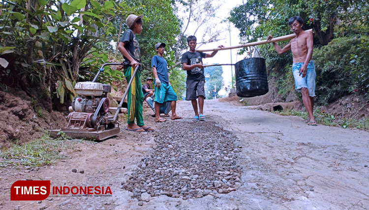 Warga Dusun Papring, Kalipuro, Banyuwangi, gotong royong mengaspal jalan secara swadaya. (FOTO: Agung Sedana/TIMES Indonesia)
