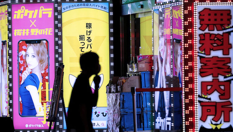 Seorang pria yang mengenakan masker berjalan melewati papan nama sebuah bar di distrik Kabukicho, di tengah wabah COVID-19 di Tokyo, Jepang, pada hari Selasa. (Foto: The Jakarta Post/Reuters-Kim Kyung-Hoon)