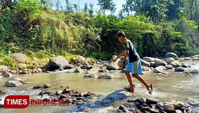 Untuk ke rumah temannya demi nebeng handphone, Wahyu harus menyeberang Kali Catur. (Foto: Aditya Candra/TIMESIndonesia)
