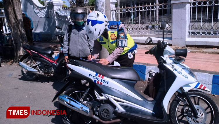 Anggota Satlantas Polres Bangkalan menilang pengendara sepeda motor yang melanggar peraturan lalu lintas. (FOTO: Doni Heriyanto/TIMES Indonesia)