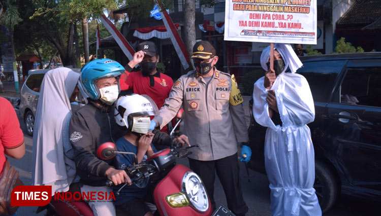 Kapolres Bondowoso AKBP Erick Frendriz didampingi pocong jadi-jadian saat membagikan ribuan masker ke sejumlah warga di Alun-Alun RBA Ki Ronggo (Foto: Moh Bahri/TIMES Indonesia)