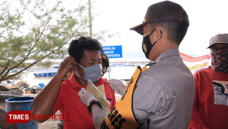 Suasana saat pembagian masker dan sosialisasi kepada Nelayan TPI Tamperan oleh Kapolres Pacitan bersama jajaran serta TNI. (Foto: Rojihan/TIMES Indonesia)