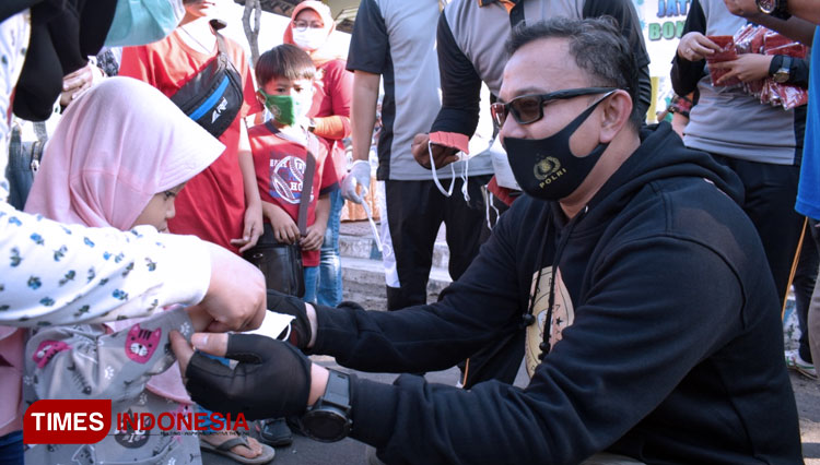 Kapolres Bondowoso AKBP Erick Frendriz saat memasangkan masker ke anak-anak yang melintas di Alun-Alun RBA Ki Ronggo. (FOTO: Moh Bahri/TIMES Indonesia)