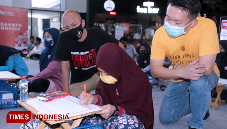 Ketua Katalis, Rony (kiri) bersama Presiden Rotary Club Surabaya West, Michael Agusta saat mendampingi peserta menggambar manga. (Foto: Inntan Wulandari/TIMES Indonesia)