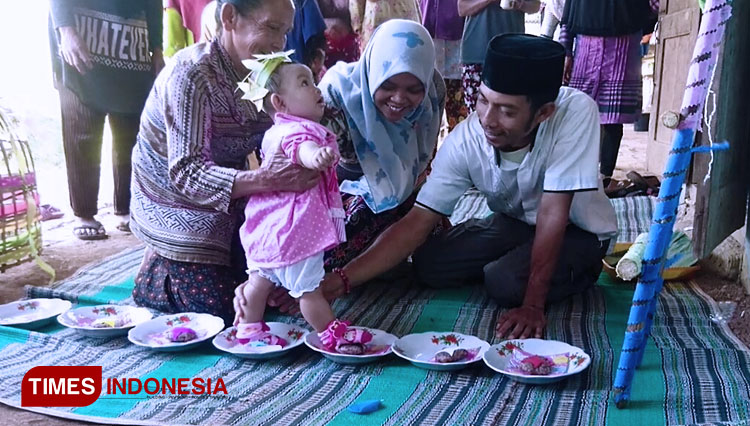 A baby walks on plate filled with red and white porridge as one of the ritual at tedhak siten ceremony at Selur, Ngrayun, Ponorogo. (Photo: Taufiq Arrahman/TIMES Indonesia)