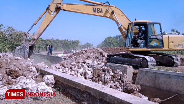 Kendaraan alat berat excavator proyek Jalan Lingkar Selatan (JLS) saat mengeruk kembali gundukan tanah menutupi aliran sungai irigasi persawahan di Kecamatan Kota Tuban, Kabupaten Tuban (09/09/2020). (Ahmad Istihar/TIMES Indonesia) 