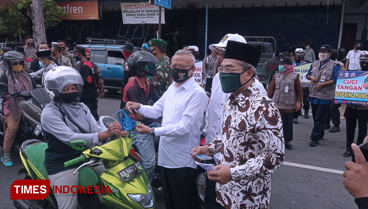 Suharsoni dan Abdul Halim Muslih membagikan masker kepada pengguna jalan di Bantul (Foto: Totok Hidayat/TIMES Indonesia)